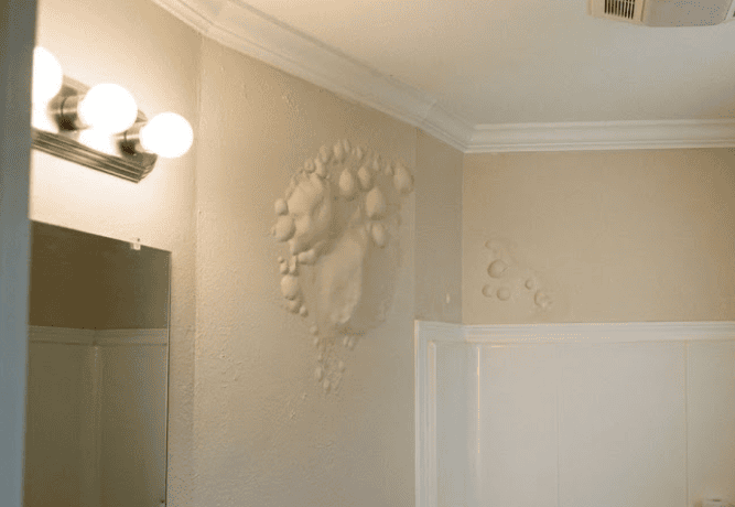 Severe paint bubbling and blistering on bathroom wall caused by moisture in a Hampton Roads VA home