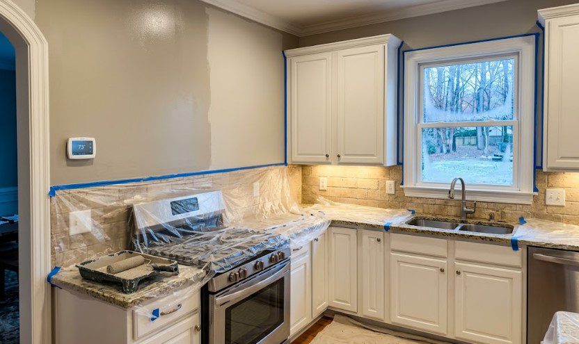 Kitchen wall half-painted with the thermostat reading 73 degrees and snow outside the window