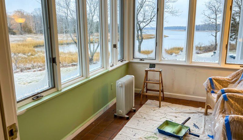 Space heater and thermometer warming a sunroom with frosted windows before painting